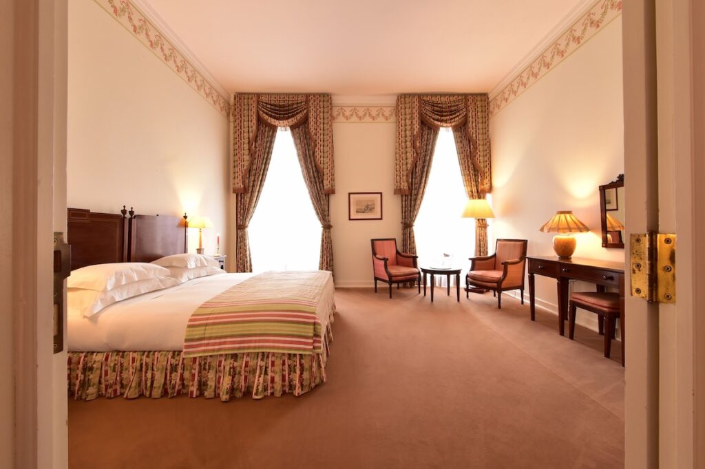 Quarto palaciano com decoração neoclássica e tons rosados, destaque das pousadas em portugal históricas.