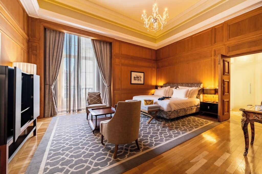 Quarto luxuoso com painéis de madeira e lustre de cristal, destaque das pousadas em portugal na capital.