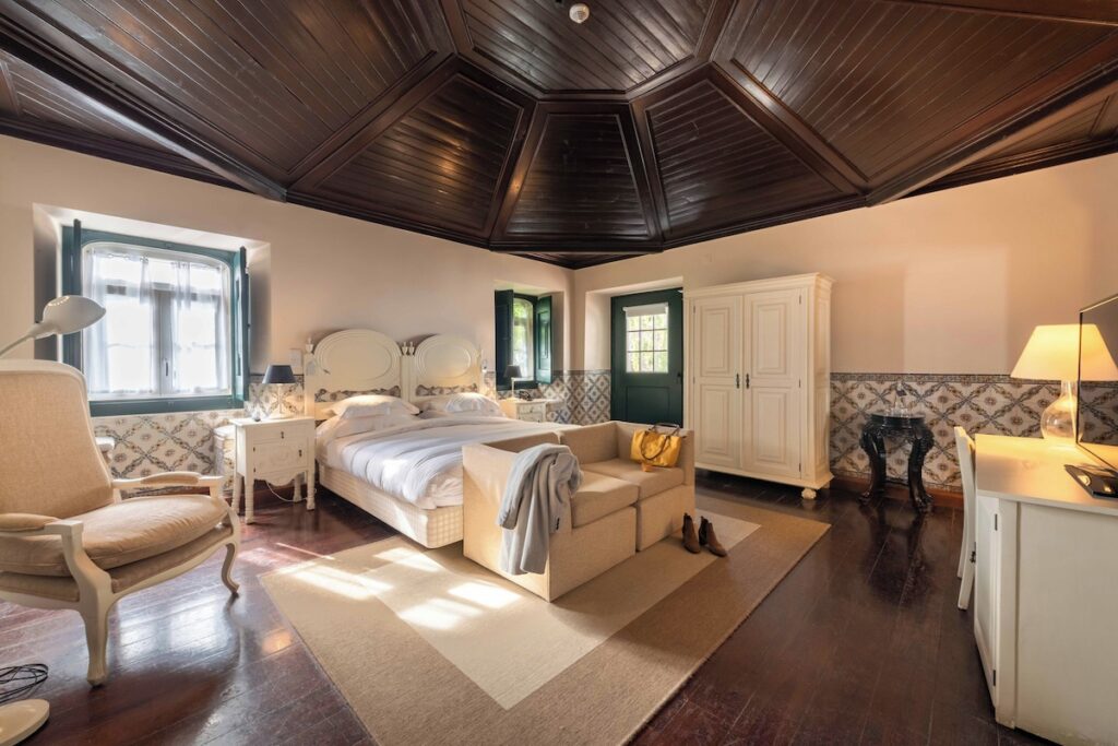 Quarto histórico com teto de madeira e azulejos em uma das pousadas em portugal dentro de um castelo.