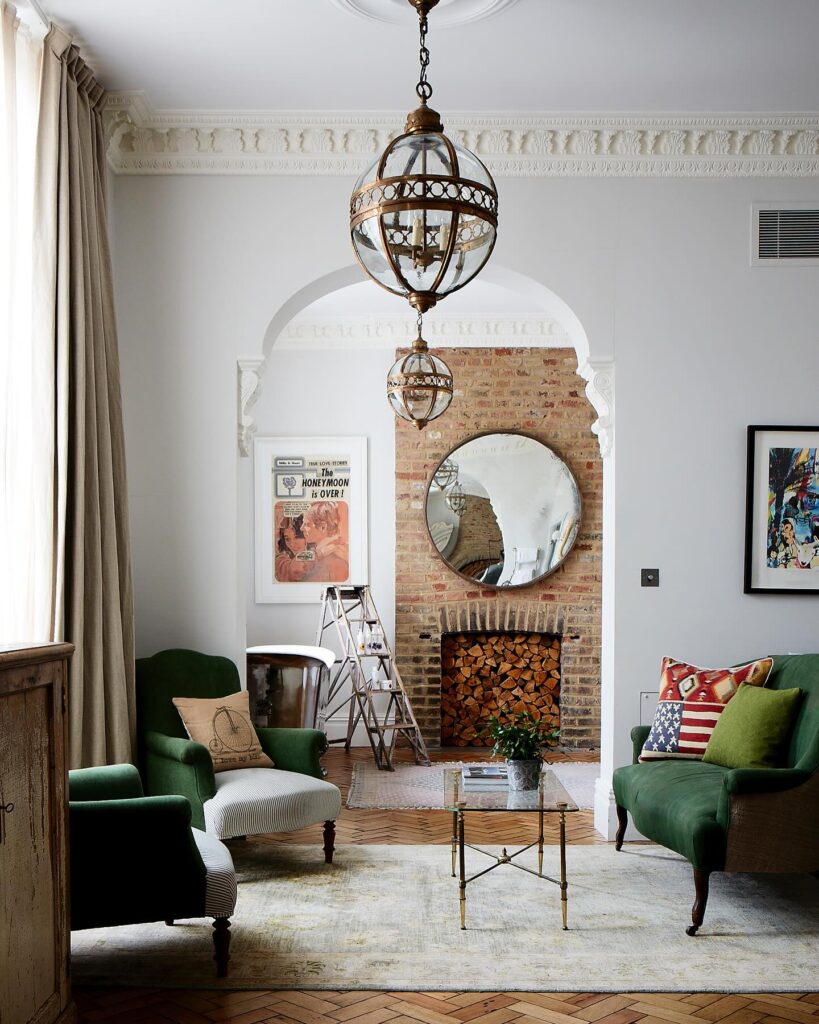 Sala de estar de hotéis boutique em londres com lareira de tijolos, poltronas verdes e piso de madeira parquet.