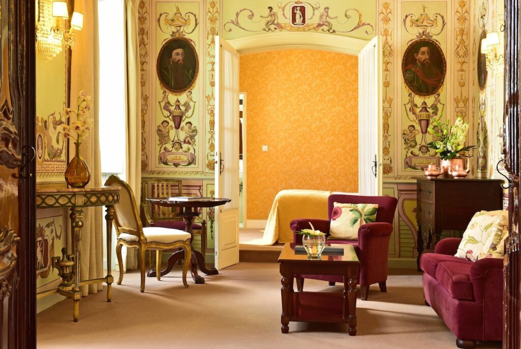 Sala de estar luxuosa com afrescos e móveis de época, marca das pousadas em portugal históricas.