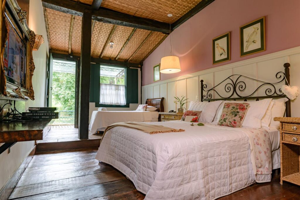 Quarto rústico com teto de palha e cama de ferro em fazendas históricas para se hospedar no interior do Rio.