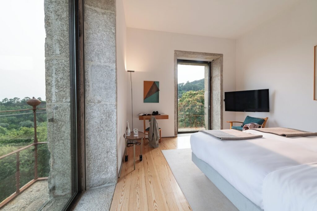 Quarto com paredes de pedra e vista para a natureza, destaque das pousadas em portugal com arquitetura de Souto de Moura.