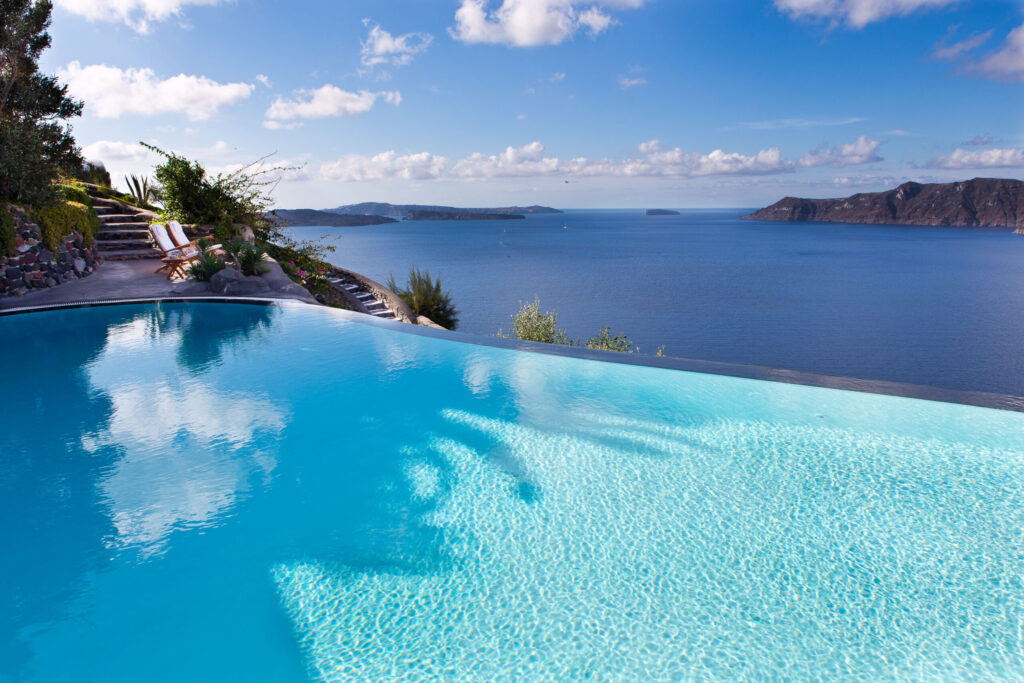 Piscina infinita icônica fundindo-se com o mar Egeu em hoteis boutique em santorini.