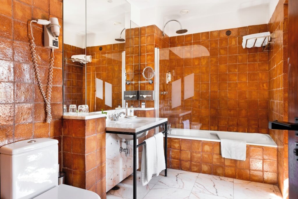 Banheiro com azulejos ocre e bancada de mármore, detalhe de design nas pousadas em portugal.