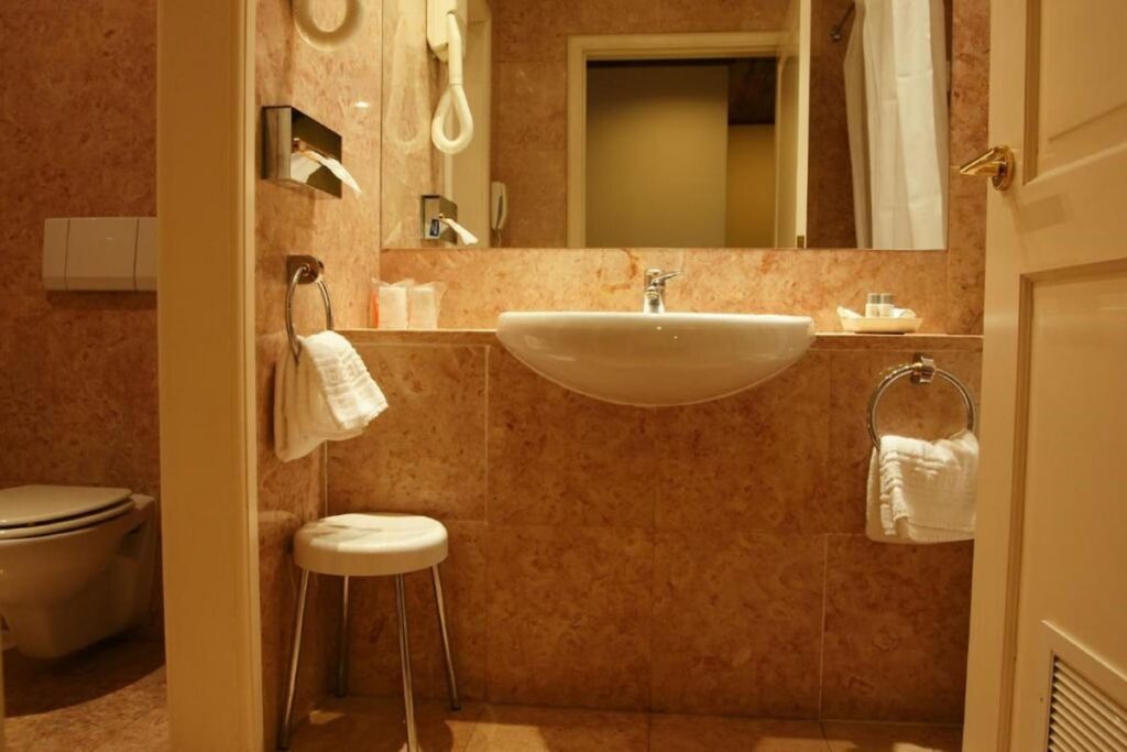 Banheiro luxuoso em mármore rosado, elegância clássica em uma das pousadas em portugal.