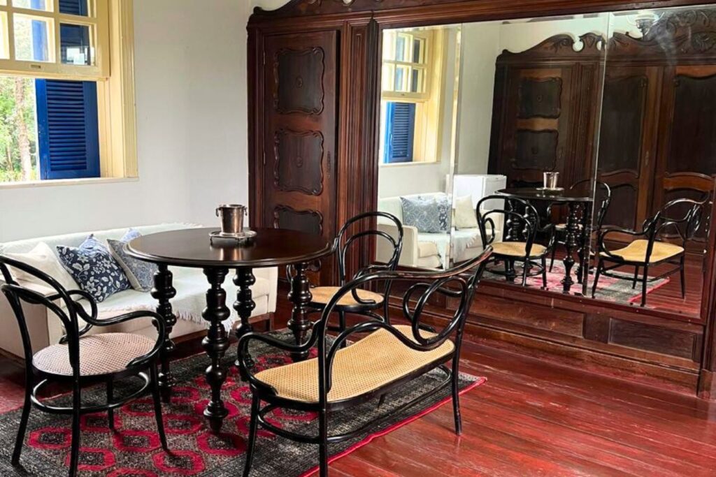 Sala de estar vintage com móveis de madeira e espelho grande, ideal para quem busca fazendas históricas para se hospedar.