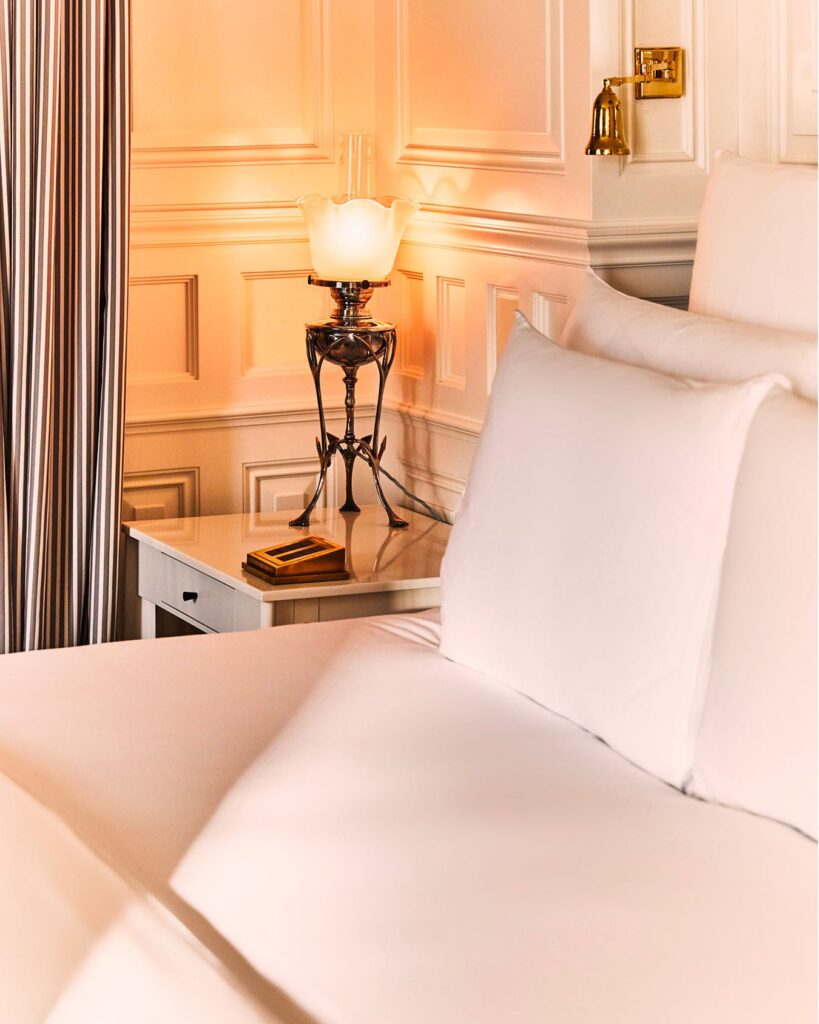 Detalhe de luminária vitoriana em mesa de cabeceira branca em hotéis boutique em londres.