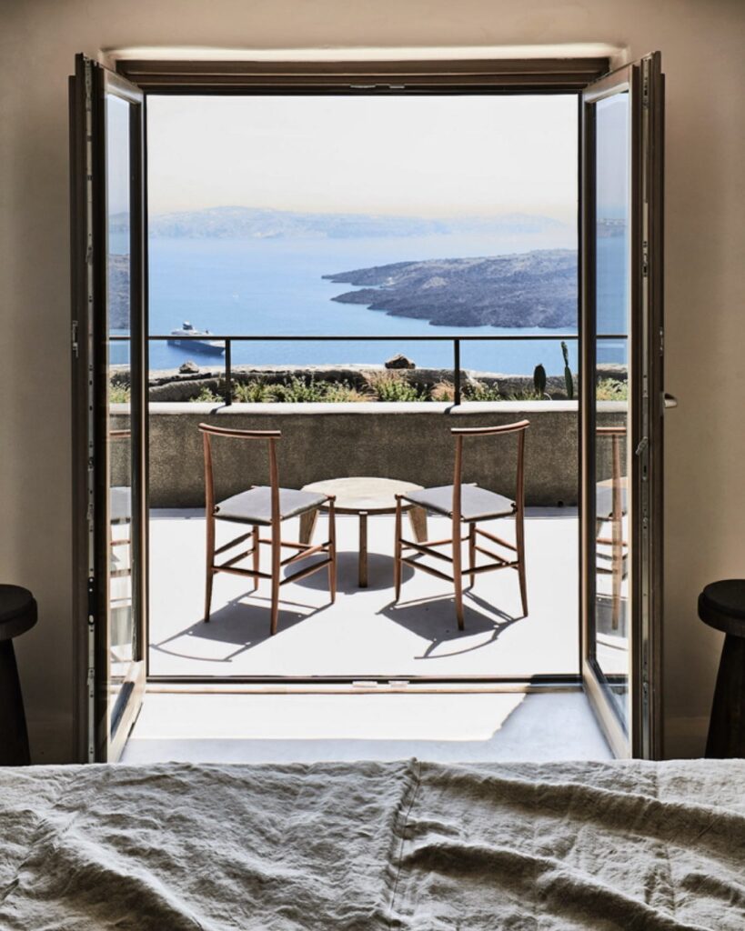 Varanda com cadeiras de design e vista panorâmica para o mar, destacando a experiência nos hotéis boutique em santorini.