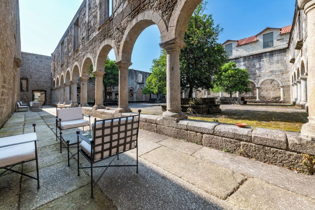 Pátio histórico com arcadas e laranjeiras, exemplo de área externa nas pousadas em portugal.