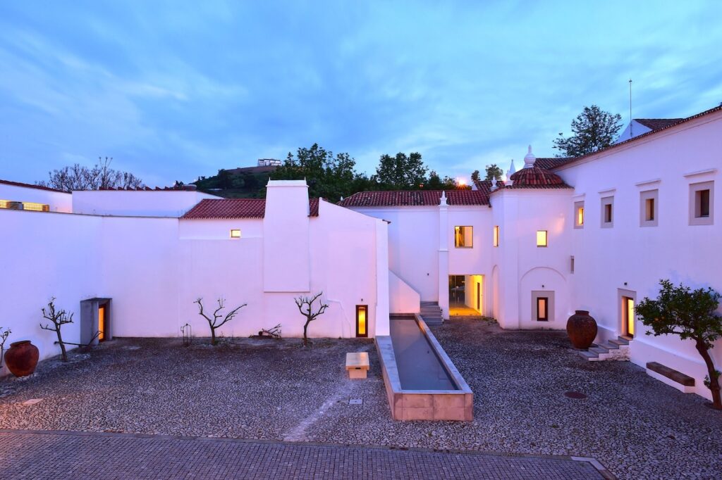 Pátio contemporâneo com espelho d'água ao anoitecer em uma das pousadas em portugal.