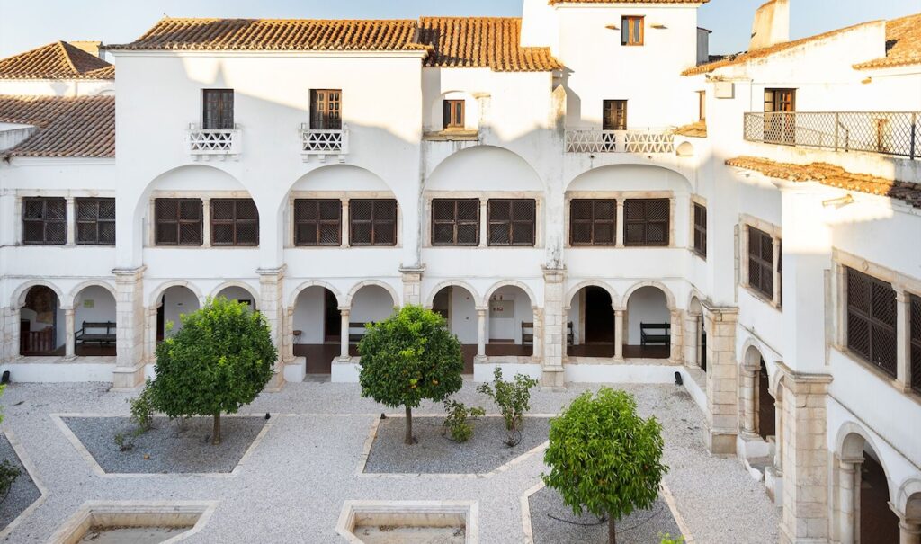 Pátio histórico com laranjeiras e arquitetura conventual, cenário das pousadas em portugal alentejanas.