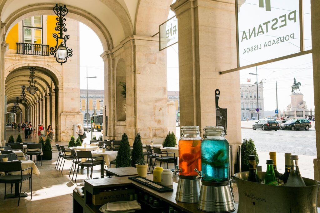 Esplanada sob arcadas históricas com vista para a praça, experiência única nas pousadas em portugal.