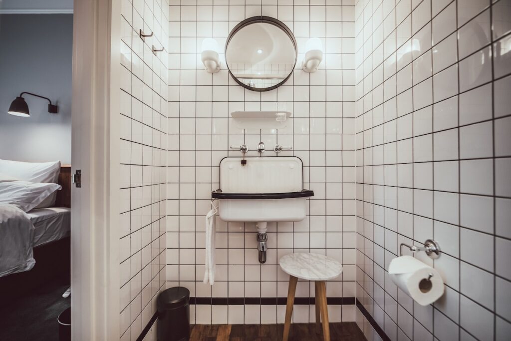 Banheiro utilitário com azulejos brancos e pia industrial em hotéis boutique em londres.