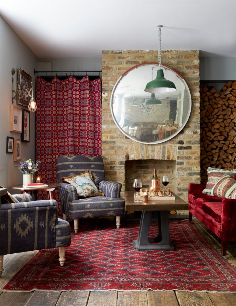 Estar aconchegante de hotéis boutique em londres com lareira, tapete oriental vermelho e poltronas azuis.