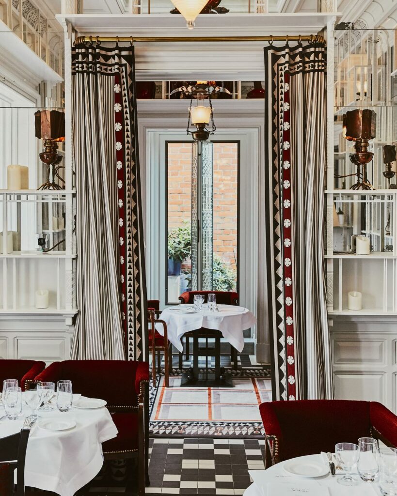 Sala de jantar elegante de hotéis boutique em londres com poltronas de veludo bordô e piso quadriculado.