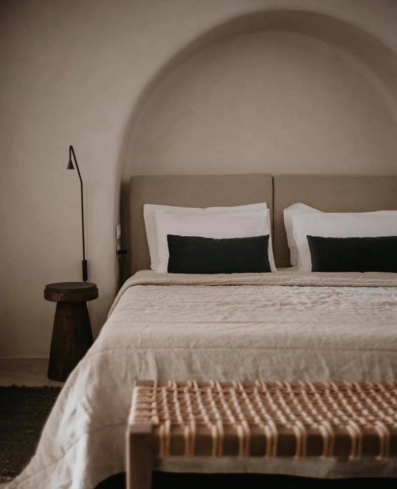 Quarto de luxo com nicho arqueado e decoração minimalista, ideal para quem busca hotéis boutique em santorini.