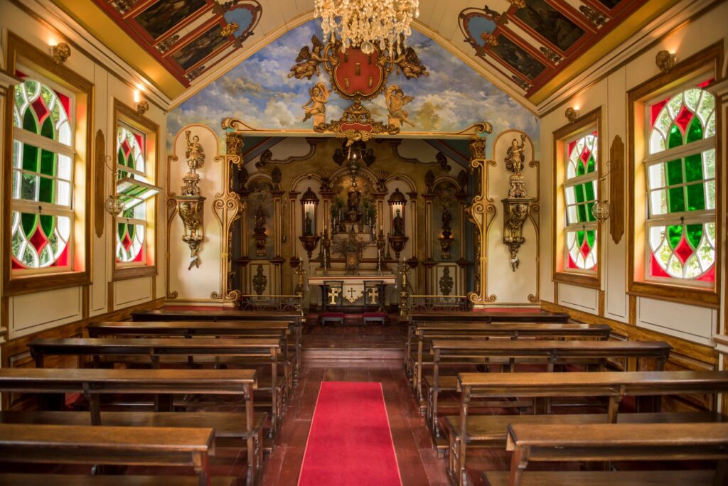 Capela barroca com altar dourado e vitrais, riqueza arquitetônica de fazendas históricas para se hospedar.