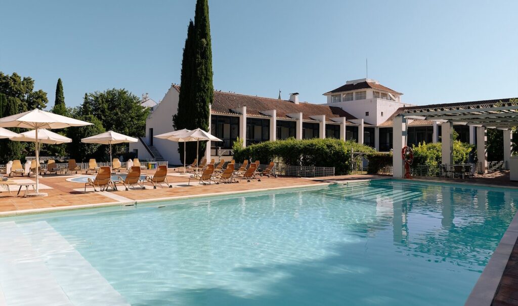 Piscina externa com vista para o edifício histórico, lazer sofisticado nas pousadas em portugal.