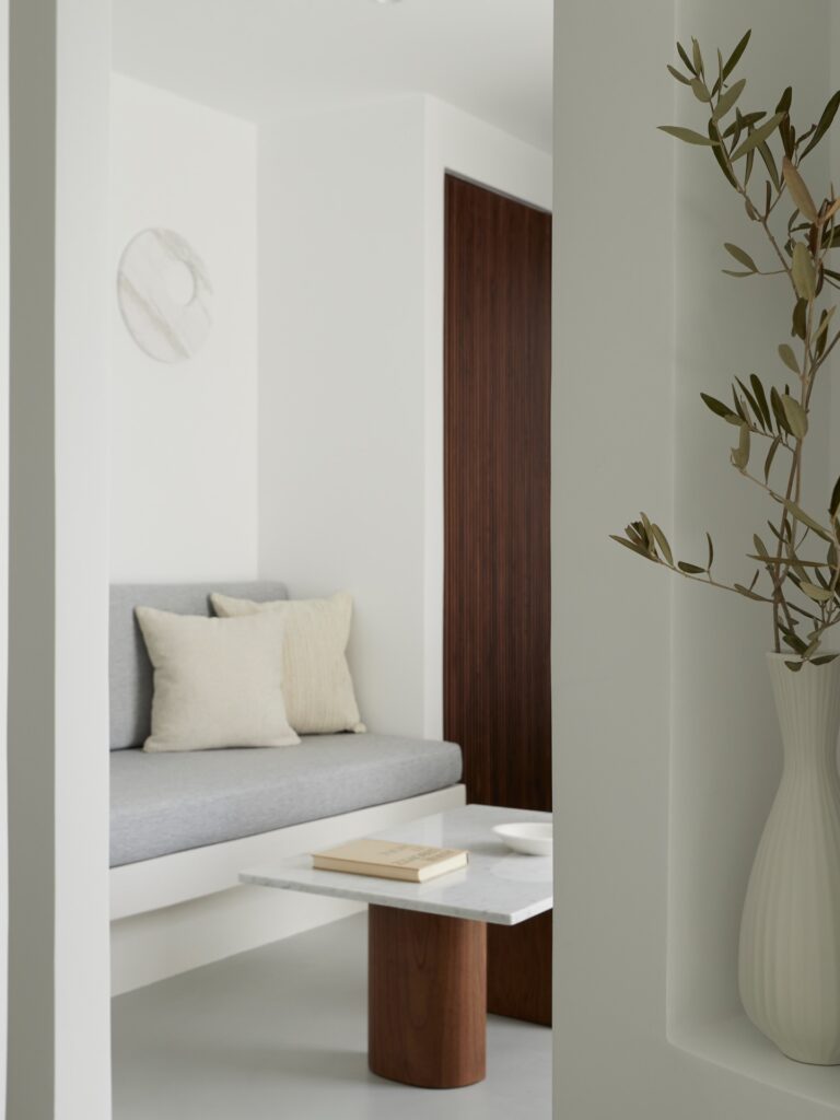 Canto de descanso minimalista com móveis de design e ramos de oliveira em hoteis boutique em santorini.