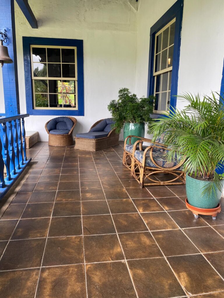 Varanda colonial com móveis de fibra e detalhes em azul, típica das melhores fazendas históricas para se hospedar.