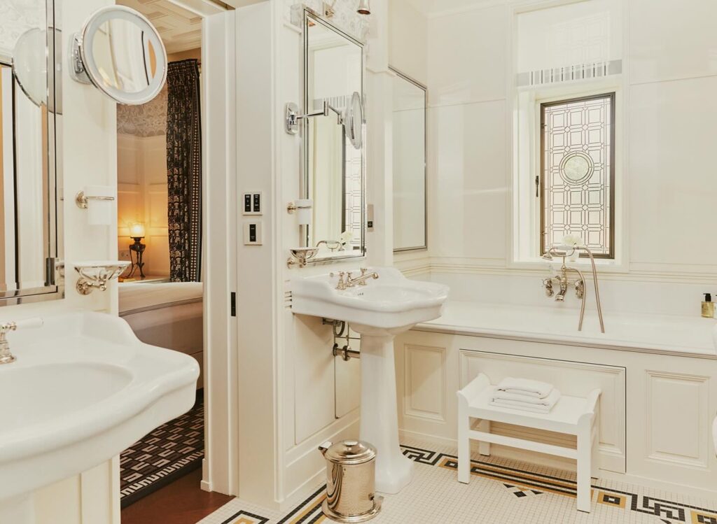 Banheiro vitoriano de luxo em hotéis boutique em londres com banheira, vitral e pia de pedestal.