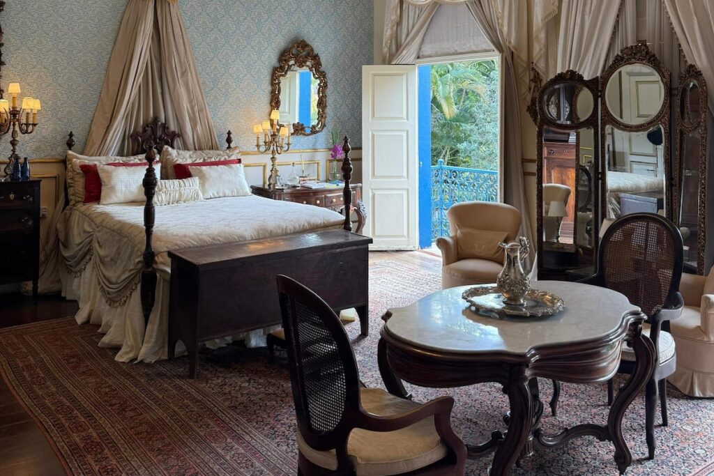Quarto de luxo com cama de dossel e mobiliário de antiquário nas melhores fazendas históricas para se hospedar no RJ.