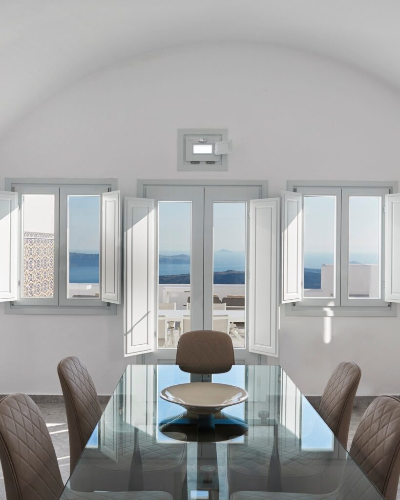 Sala de jantar elegante com mesa de vidro e vista para o mar em hoteis boutique em santorini.