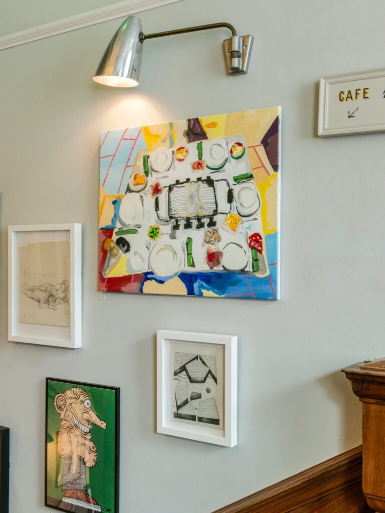 Gallery wall com quadros ecléticos e arandela vintage em corredor de hotéis boutique em londres.