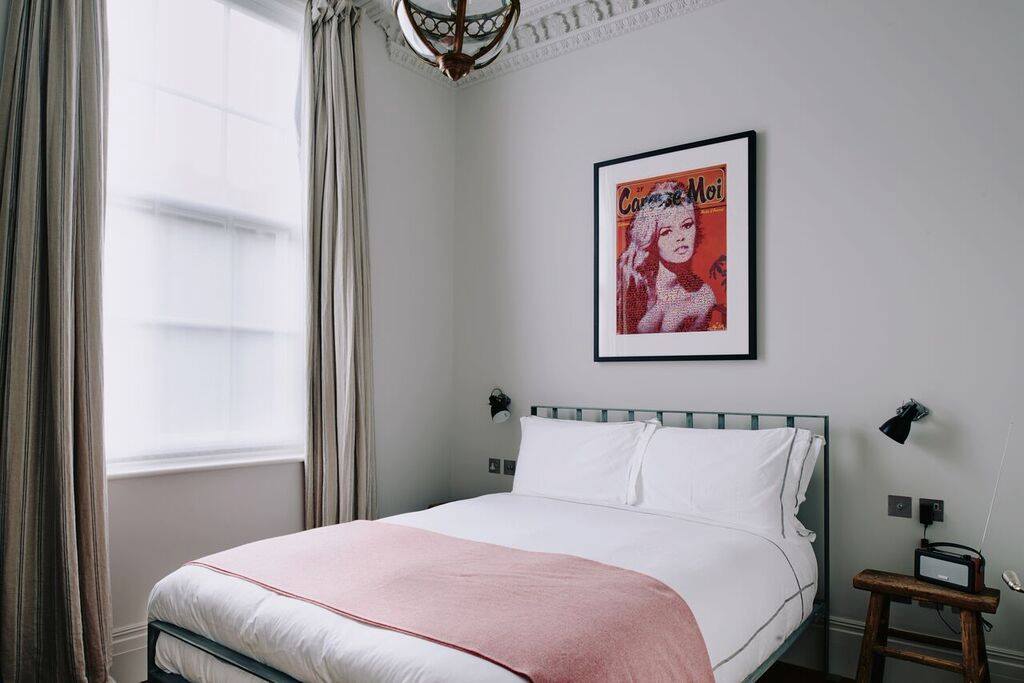 Quarto de hotel com quadro pop art, manta rosa e rádio vintage em hotéis boutique em londres.