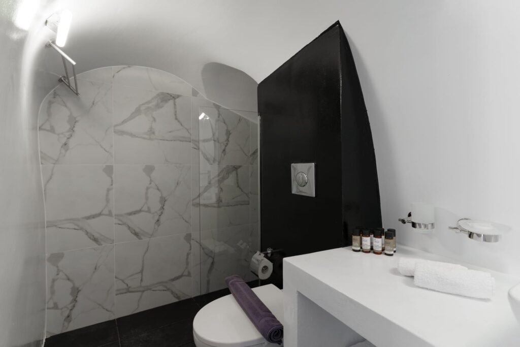 Banheiro moderno com teto abobadado e revestimento marmorizado em hoteis boutique em santorini.