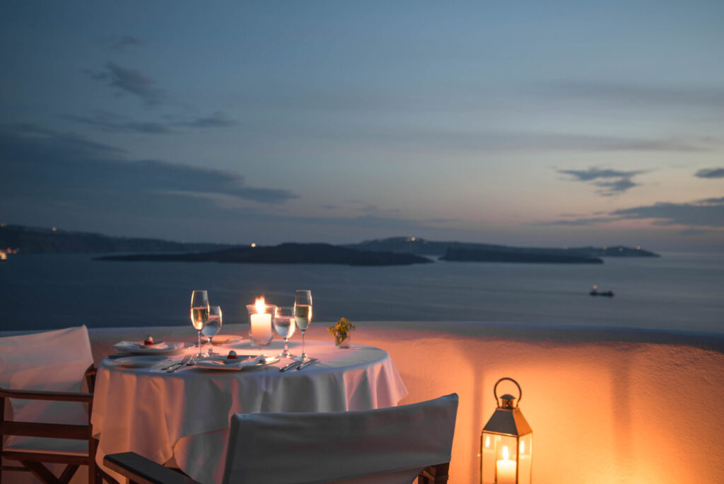 Jantar romântico ao ar livre com velas e vista para a caldeira em hoteis boutique em santorini.