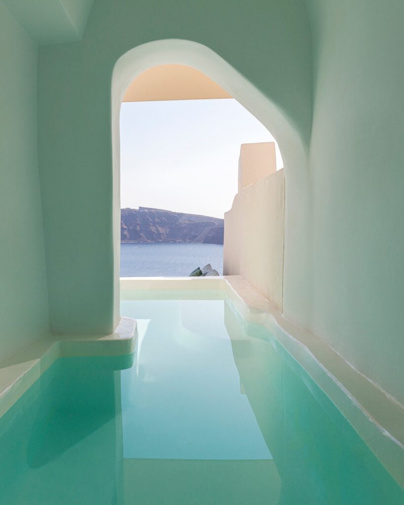 Piscina privativa emoldurada por arco em hoteis boutique em santorini, vista para a caldeira.