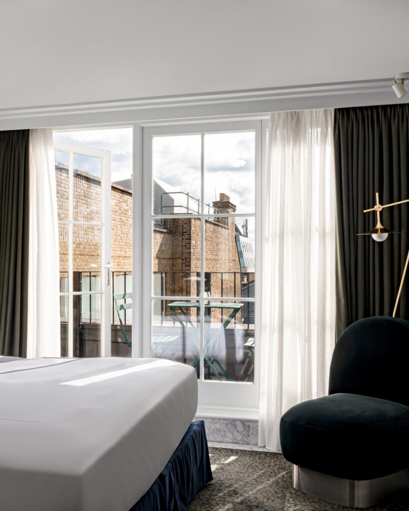 Suíte luxuosa com varanda e poltrona de veludo azul em hotéis boutique em londres.