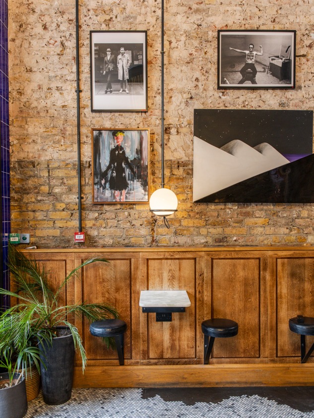 Detalhe de parede de tijolos com mesa de mármore suspensa e quadros em hotéis boutique em londres.