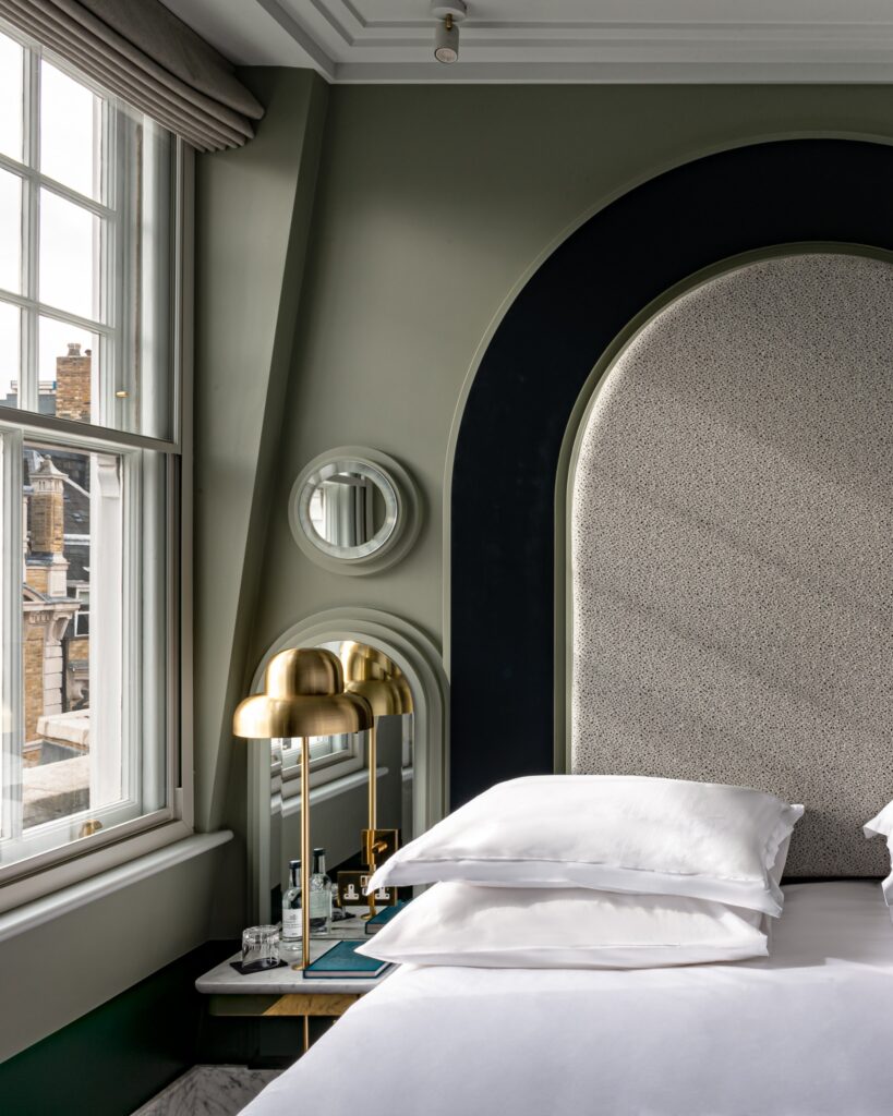 Design de interiores simétrico com cabeceira gigante e mármore em hotéis boutique em londres.