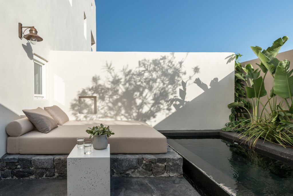 Terraço privativo com daybed e piscina de águas escuras em hoteis boutique em santorini.