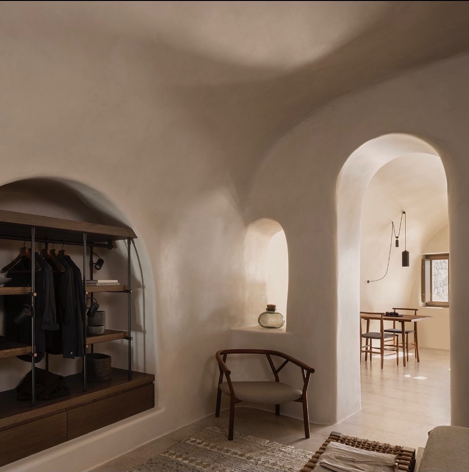Vista dos arcos internos e sala de jantar minimalista, exemplo de sofisticação nos hotéis boutique em santorini.