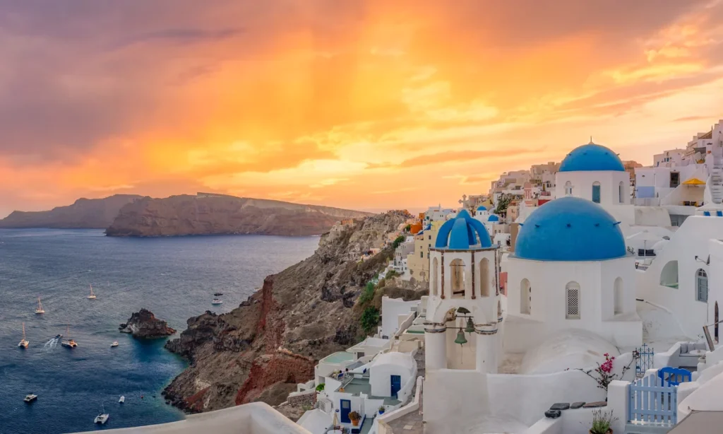 Pôr do sol dourado sobre as cúpulas de Oia, um cenário imperdível na melhor época para visitar Santorini.