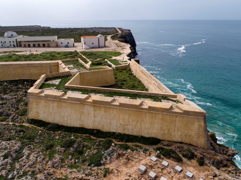 Vista aérea da Fortaleza de Sagres na Costa Vicentina durante a melhor época para visitar portugal, mostrando muralhas históricas e mar azul.