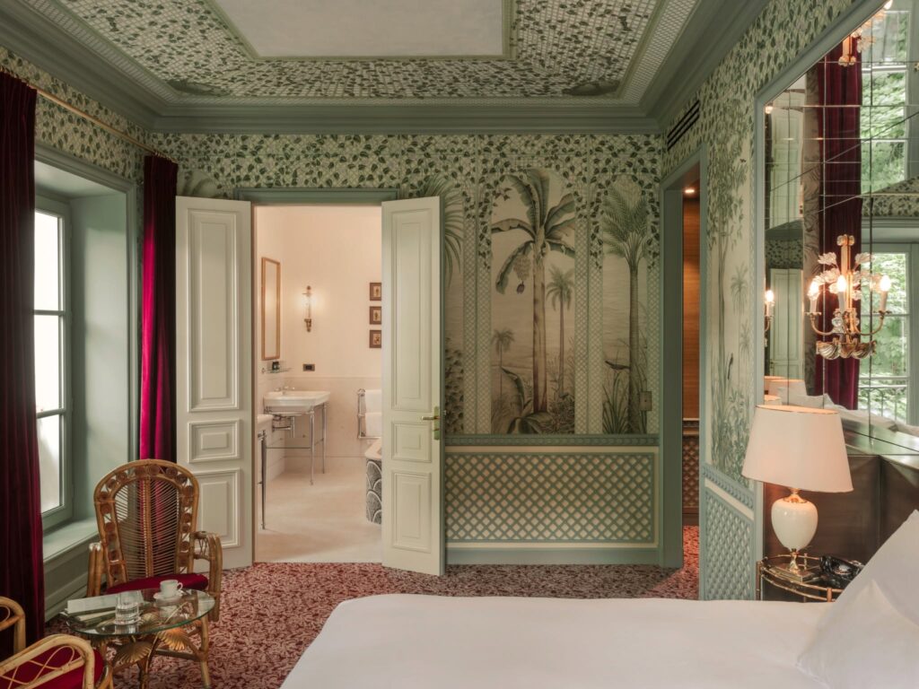 Suíte clássica decorada com papel de parede botânico verde e cortinas de veludo vermelho no Hôtel Particulier Montmartre, referência em hoteis boutique em paris.