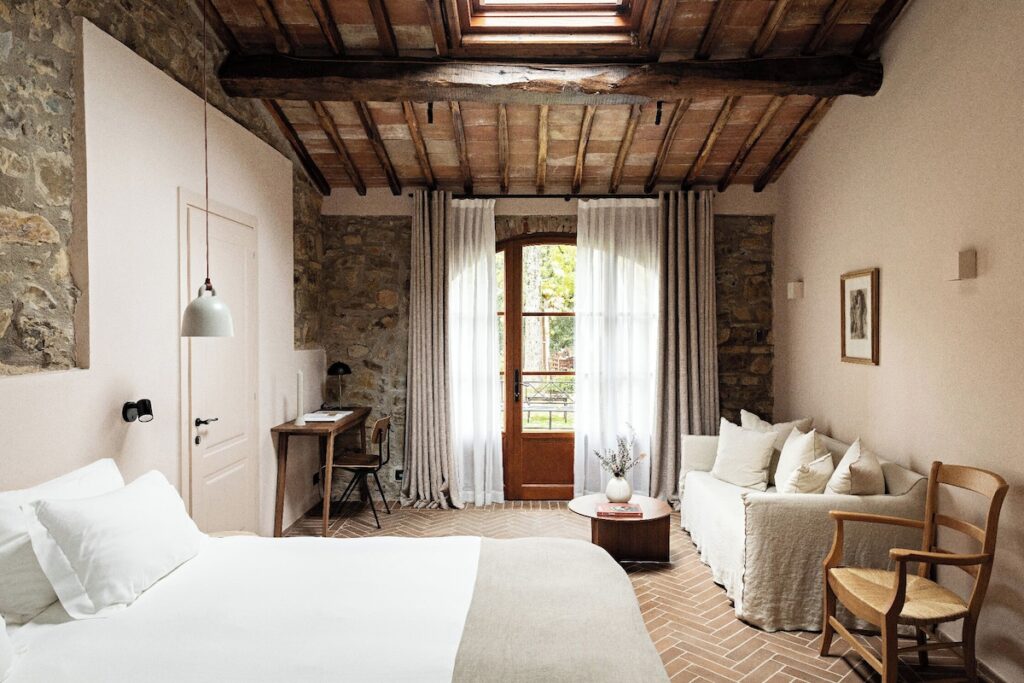 Quarto histórico toscano com vigas de madeira e terracota no Pieve Aldina, ideal para lua de mel na europa.