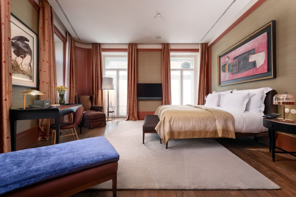 Quarto elegante do Bairro Alto Hotel, um dos hoteis boutique em lisboa, com paredes verde sálvia, cabeceira de cama clássica e detalhes em terracota.