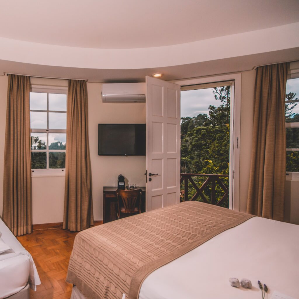 Quarto de um dos hotéis românticos em são paulo com cama de casal e varanda voltada para a natureza de Campos do Jordão.
