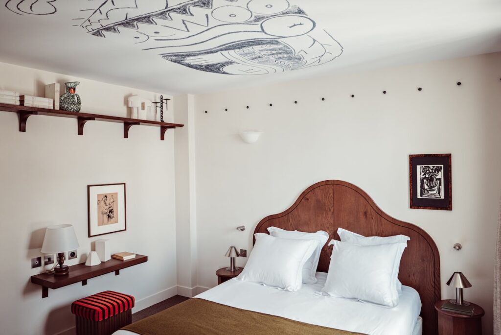 Quarto elegante no Hôtel des Académies et des Arts, um dos principais hoteis boutique em paris, com cabeceira de madeira, teto pintado à mão e móveis de design.