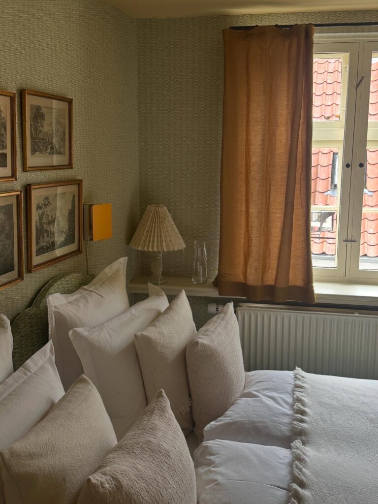Quarto nórdico com papel de parede geométrico e cortina ocre no The Monica, micro-hotel para lua de mel na europa.