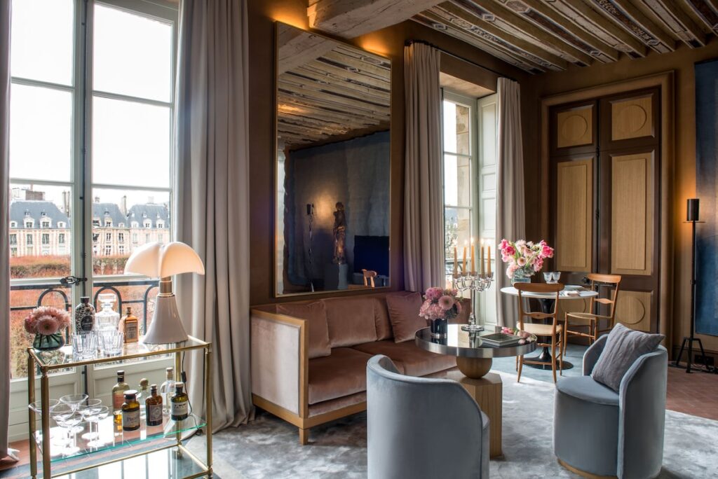 Sala de estar clássica com teto pintado e sofá de veludo no Cour des Vosges, um dos mais exclusivos hoteis boutique em paris.