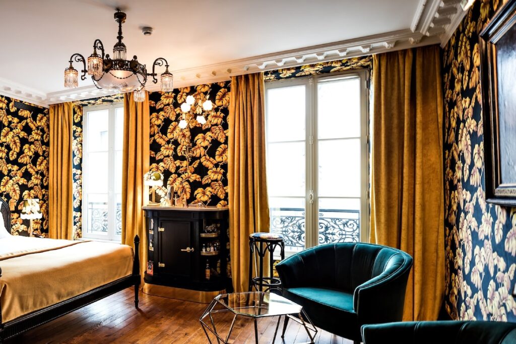 Quarto com design maximalista no Hôtel Providence -Canal Saint -Martin, entre os hoteis boutique em paris, com papel de parede dourado e poltrona azul.
