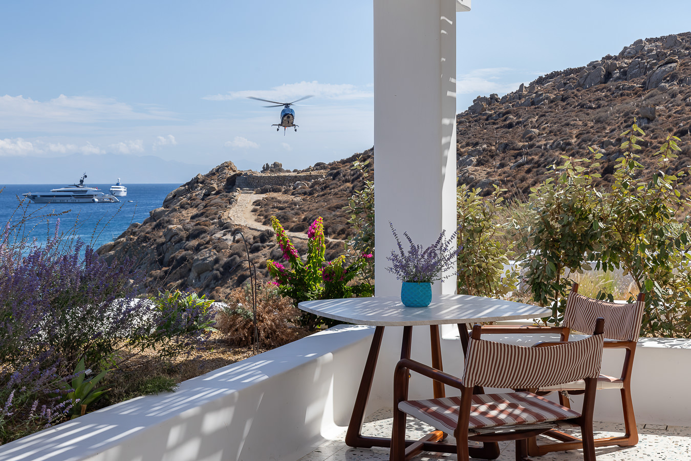 Terraço privativo com mesa de mármore e cadeiras listradas da Loro Piana no Nammos Hotel, sofisticado resort em Mykonos.