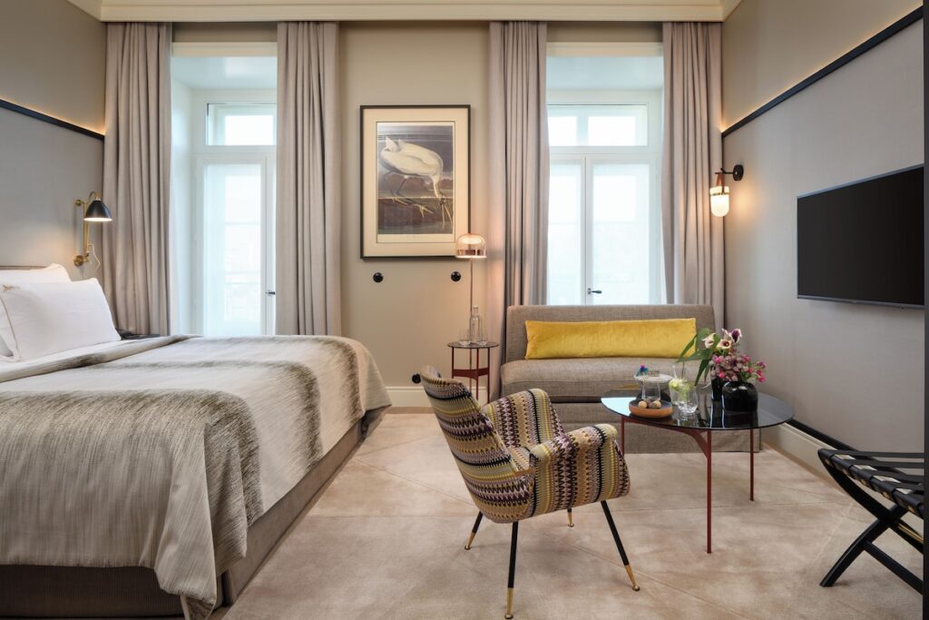 Suíte moderna no Bairro Alto Hotel, opção charmosa entre os hoteis boutique em lisboa, com área de estar, poltrona estampada e detalhes em mostarda.